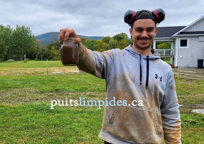 Antoine tient dans sa main un bocal d'eau de curage ce puits souffrait d'un encrassement par l'eau ferreuse